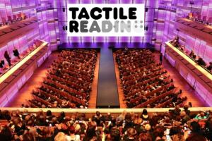 Zaal in het Muziekgebouw, Amsterdam met het logo van Tactile Reading op een groot scherm