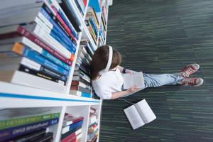 Leerling zit voor boekenkast in de bibliotheek