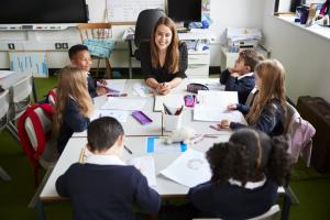 Leraar met 7 kinderen van de basisschool aan één tafel