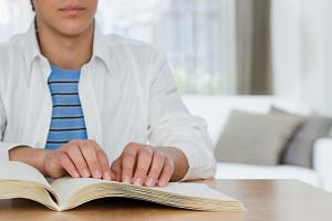 Student leest brailleboek met handen