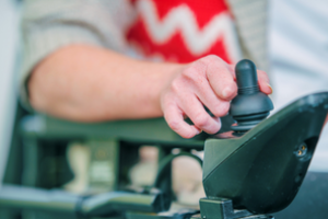 closeup van een hand die met joystick zijn rolstoel bedient