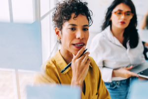 tweetal mensen in gesprek voor een board met post-it-blaadjes