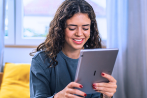 jonge vrouw bekijkt glimlachend iets op haar ipad