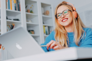 persoon met bril en hoofdtelefoon bekijk iets op een laptop