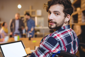jonge man kijkend naar achter over zijn schouder en met voor hem een laptop
