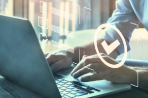 Close-up van handen en een laptop met een checkmark (vinkje) erbij