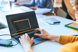 closeup van handen en laptop met op het scherm codes
