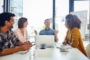 groep mensen aan vergadertafel, waarop iemand achter een laptop werkt